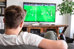 Young man watching soccer game on TV